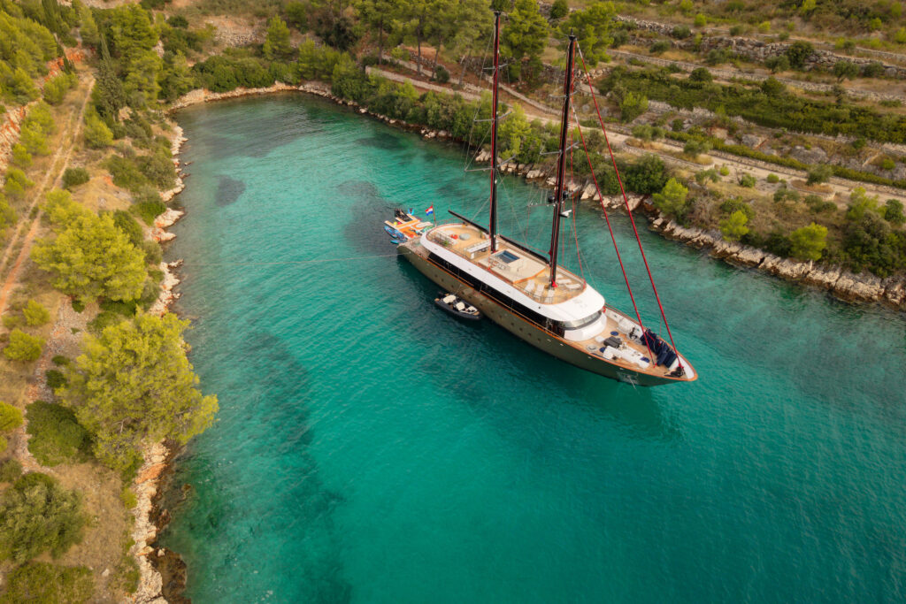 Luxury yacht at anchor in a secluded turquoise Adriatic bay, showcasing private yacht charter lifestyle in Croatia.