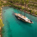 Luxury yacht at anchor in a secluded turquoise Adriatic bay, showcasing private yacht charter lifestyle in Croatia.