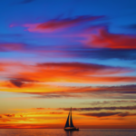 Vibrant orange and purple sunset over the Adriatic Sea with silhouettes of sailing boats, experienced during a private yacht charter in Croatia.