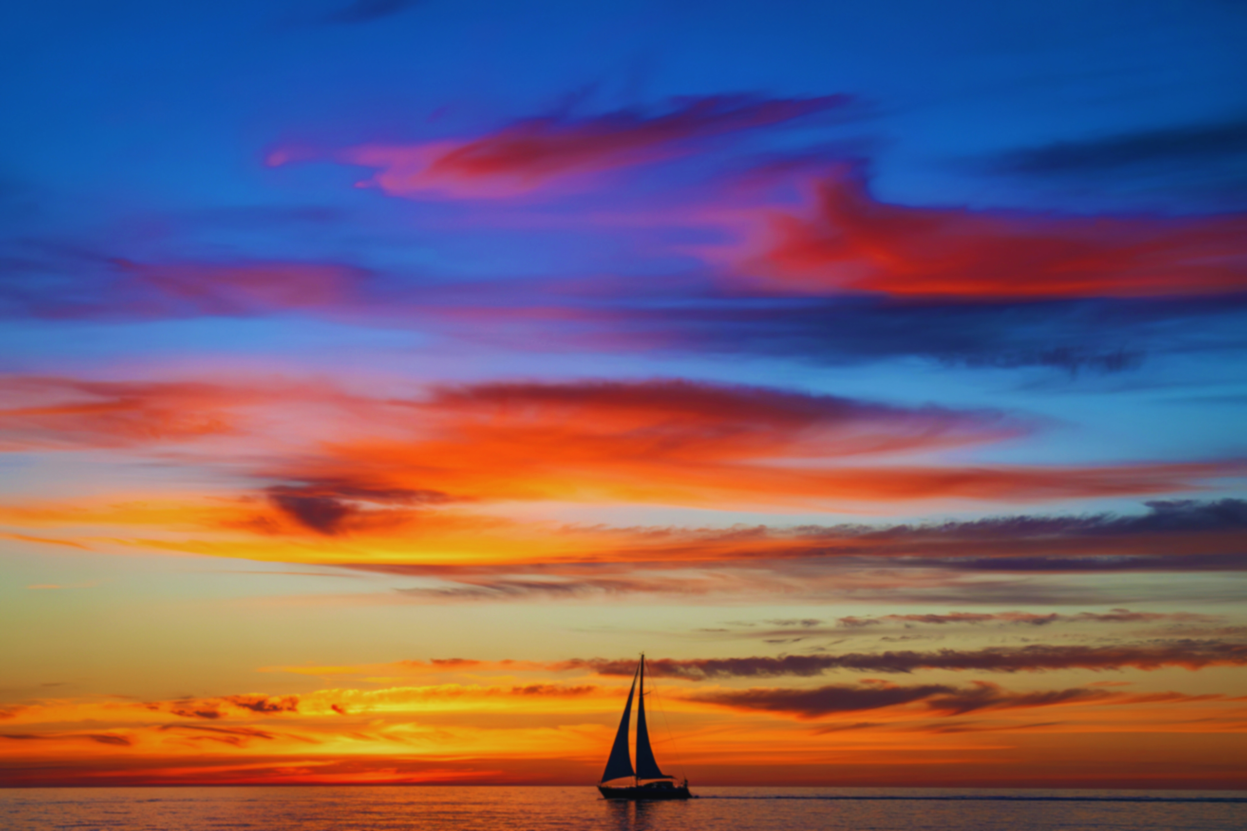 Vibrant orange and purple sunset over the Adriatic Sea with silhouettes of sailing boats, experienced during a private yacht charter in Croatia.