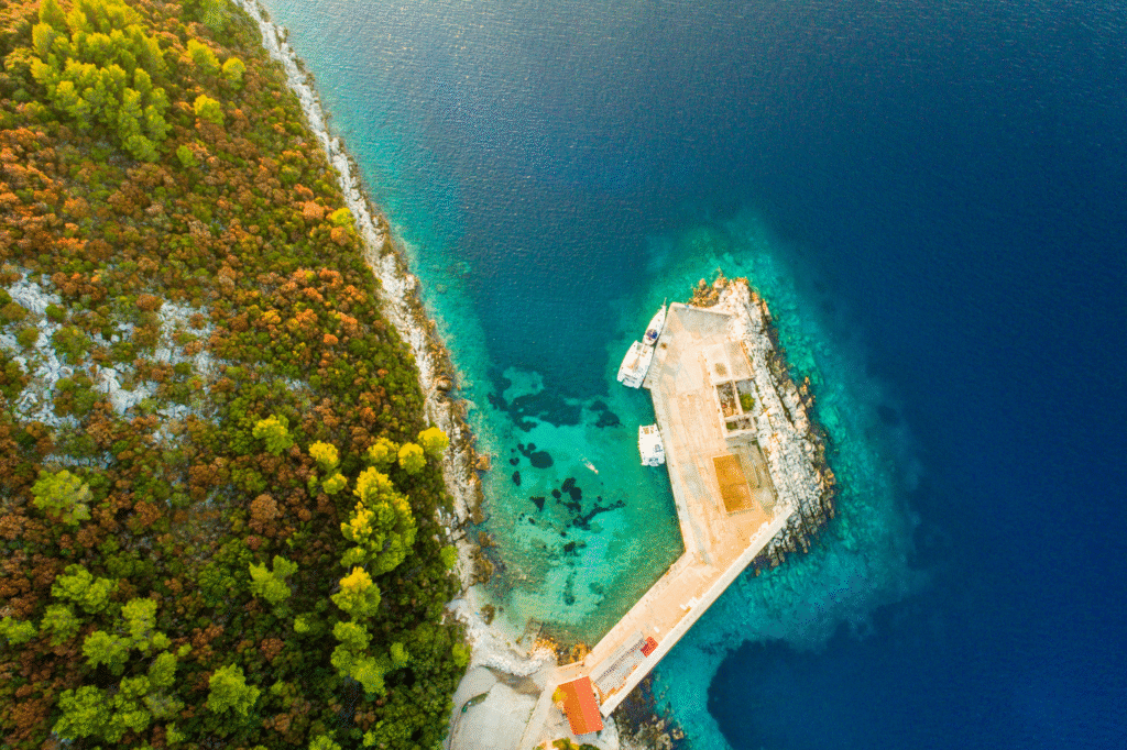 Aerial view of the rugged Lastovo archipelago coastline with deep blue sea and dense Mediterranean pine forests in Croatia.